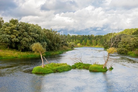 Wide river in green banks overgrown with woods