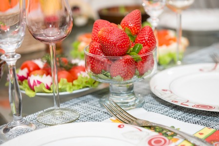 Glassware filled with strawberries on a table during dinnerの写真素材