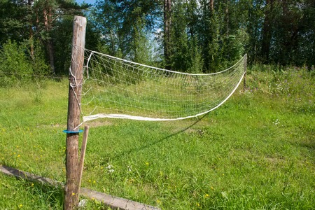 Village volleyball field with overgrown grass and sagging gridの写真素材
