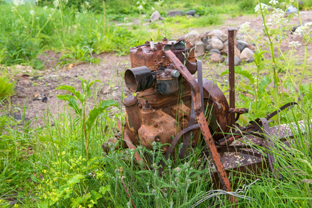Old rusty car engine is standing on the street in the grass.の写真素材