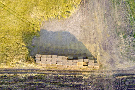 Aerial view of stacked haystack on agricultural field on autumn dayの写真素材