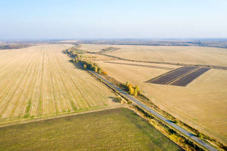 Aerial view of harvested agricultural fields and the highway in autumn day