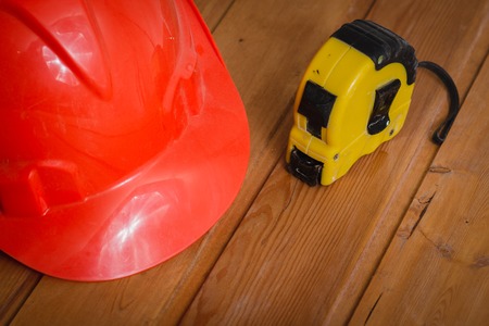 construction helmet and a tape measure on a wooden tableの写真素材