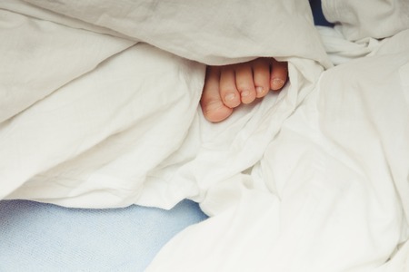 Foot of child sticking out of the white blanket