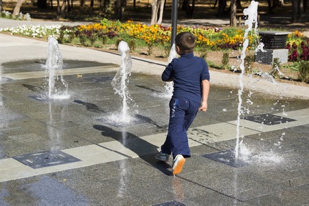The boy runs around in the fountainの写真素材