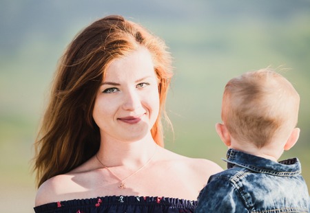 Side view of cheerful beautiful young woman holding babyの写真素材