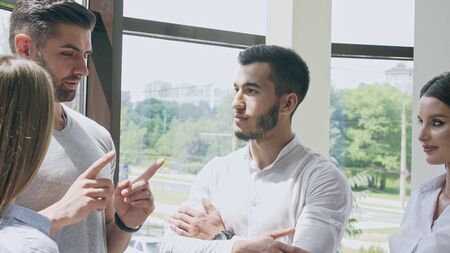 Small company of two men and two women in an office in a small talk with each otherの写真素材