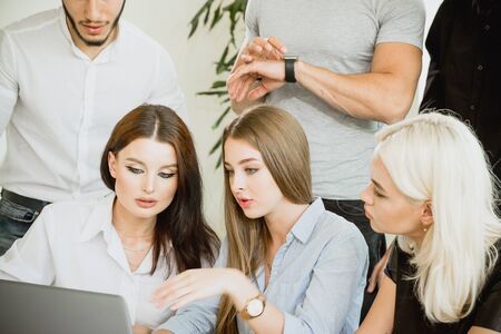 A group of young men and women are busy working on a laptop. Time is not waiting. Employees are working on a task.の写真素材