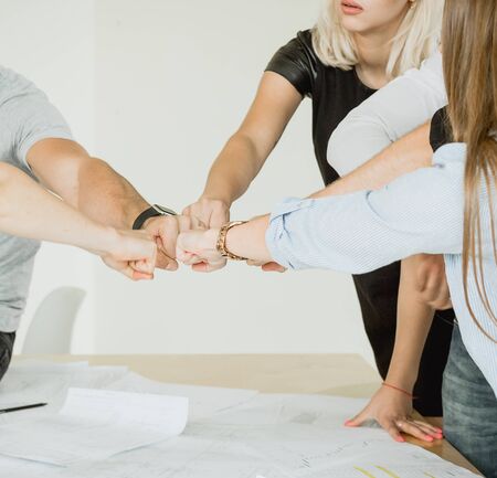 Employees cheerfully clench their fists in the center of the tableの写真素材