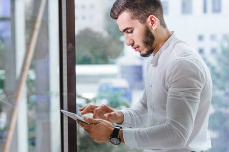 Cropped closeup of young arab ethnency man using tablet pc indoorの写真素材