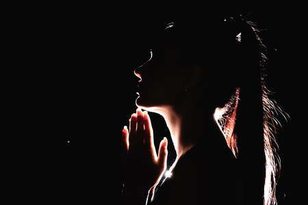 Silhouette of a woman praying indoors. Woman on a sporty physique.の写真素材