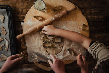 Female hands and a child make a die cut from the rolled cookie dough. Preparation for the holiday....