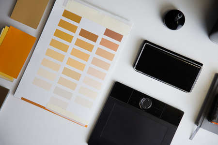 Color checkers and samples of color paint on architects table. Graphic tablet and smartphone...