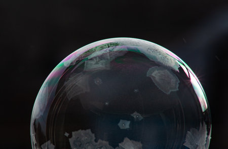 Winter collage. A transparent soap bubble freezing in the cold on a dark background. Tom 3.
