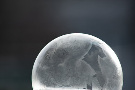Winter collage. A transparent soap bubble freezing in the cold on a dark background. Tom 17.