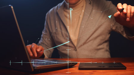 A businessman working on a laptop and graphics tablet models graphics in space on a coordinate...