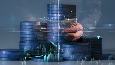 Columns of coins with graphs and a coordinate system in blue against the background of hands...