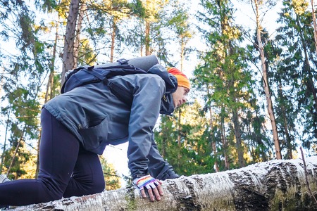 Young man climbs onto a fallen birch in the forest