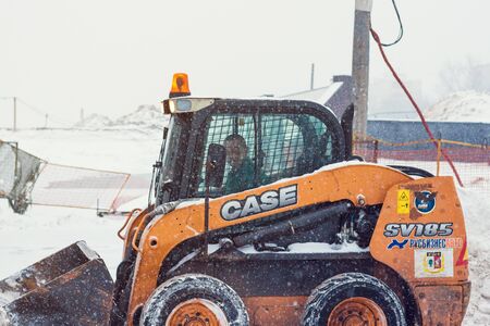 Tractor with snowplow removing snow during heavy snowfallのeditorial素材