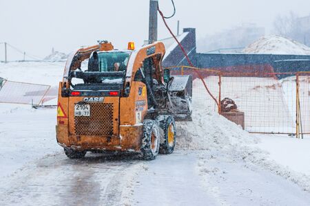 Tractor with snowplow removing snow during heavy snowfallのeditorial素材