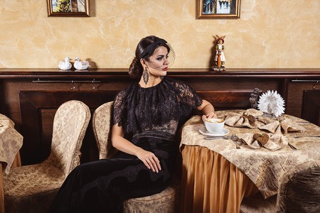 Lady in evening dress at the table in a cafe