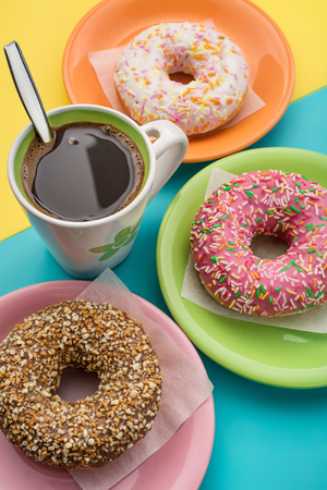 Donuts on plates and a cup of coffeeの写真素材