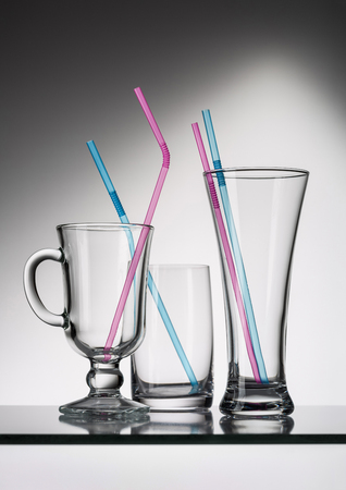 Empty transparent glasses and other utensils on gray background with reflection.の写真素材