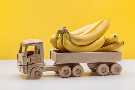 Bunch of bananas in back of toy wooden car.の写真素材