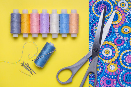Still life with accessories for needlework. Bright fabric, scissors, pins, threads on reels.の写真素材