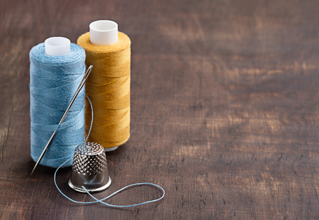 Two vertical coils of colored thread and thimble.の写真素材