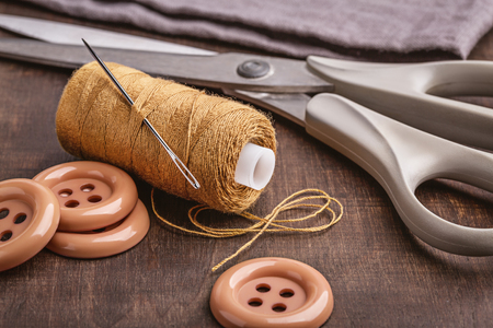 Objects for sewing on brown wooden surface.の写真素材