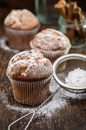 Strainer with powdered sugar and muffins.の写真素材