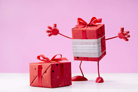 Gift in red box in protective mask. We defeat the virus. Box on legs, with handles. Copy space.の写真素材