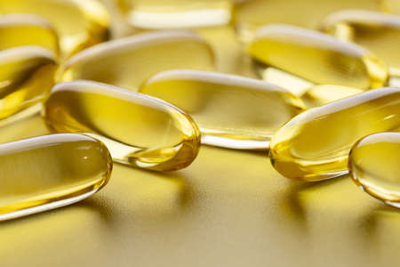 Yellow transparent capsules of fish oil on a gray background. Backgrounds and textures. Vitamins,...