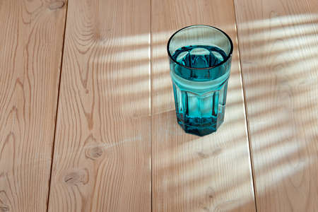 Pure water in a blue glass. Healthy lifestyle concept. Reflection on a wooden surface.