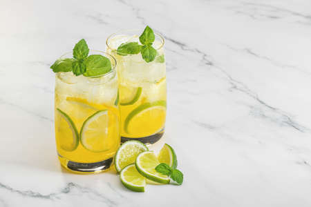 Two glasses of refreshing cocktail with lemon, lime and green mint sprigs. Close-up, copy space, marble backdrop.の写真素材