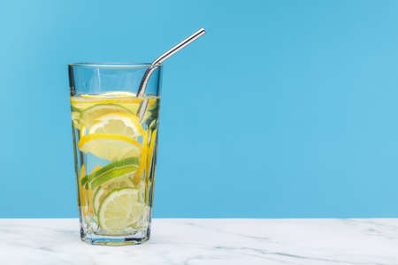 Refreshing drink with lemon and lime in a large blue glass, blue background, copy space.の写真素材