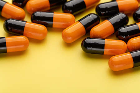 Medicinal capsules on a yellow background, close-up. Health concept, pharmaceutical medicine.の写真素材