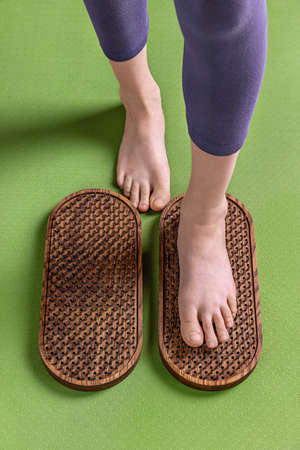 Female feet stand on a sadhu board with nails, on a green mat, yoga practice, close upの写真素材