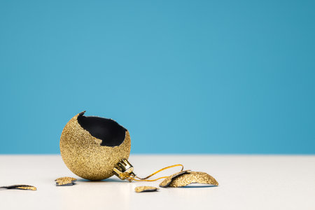 Broken New Year's golden ball. Christmas decorations, blue background. Studio shot, copy space.