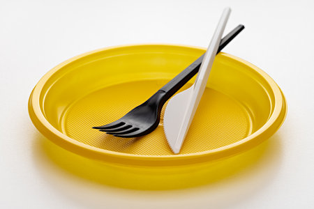 New plastic yellow plate, wine and knife on a white background.の写真素材