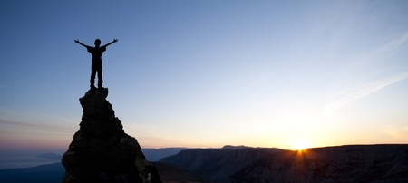 man on top of the mountain reaches for the sunの写真素材