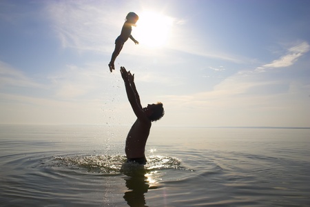 father is tossing up a child in waterの写真素材
