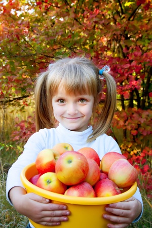 little girl with fresh vegetables in gardenの写真素材