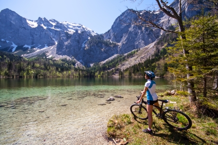 Yaung woman riding bike beside a lake in  Alps,  Salzkammergut Austriaの写真素材