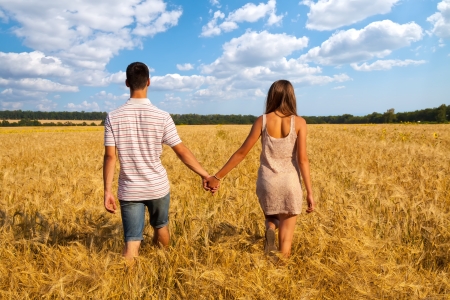 Happy young couple walking together  through wheat fieldの写真素材