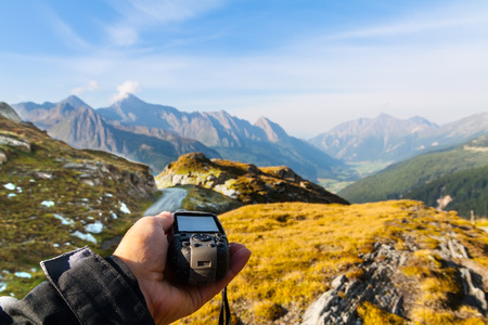 GPS navigator and hand on Alps mountain background
