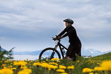 Mountain bike cyclist at flowered field, Lofoten, Norwayの写真素材