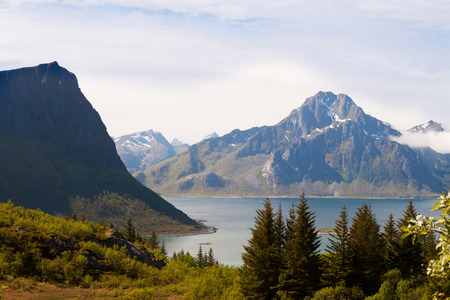 Scenic fjord on Lofoten islands with typical fishing hut and towering mountain peaks