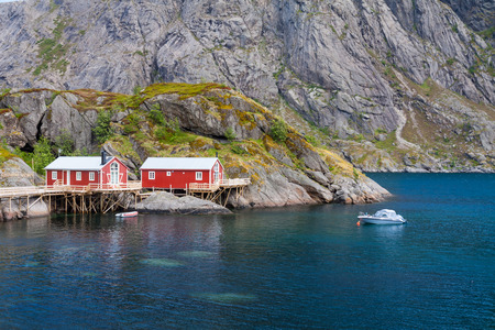 Typical red rorbu fishing hut in town of Svolvaer on Lofoten islands in Norway lit by midnight sunの写真素材